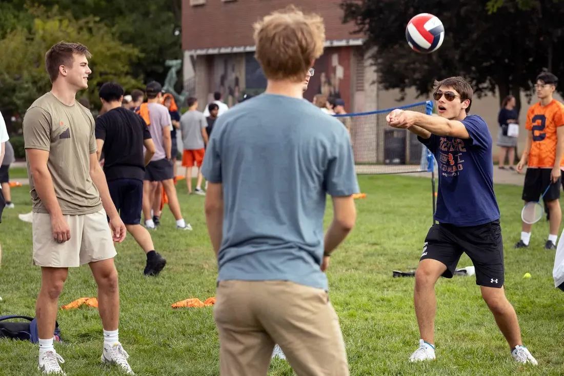 Students playing volleyball together outside.